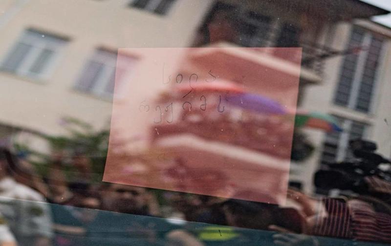 Mzia Amaghlobeli 在离开法庭时，手持一张写有“A slap to the regime”字样的纸。