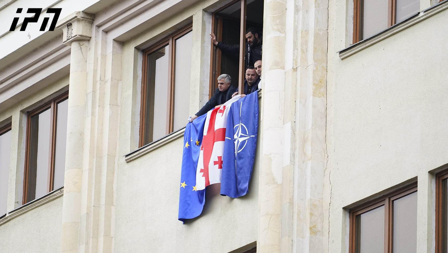 Opposition MPs display flags of European Union, NATO and Georgia from the window of Parliament building
