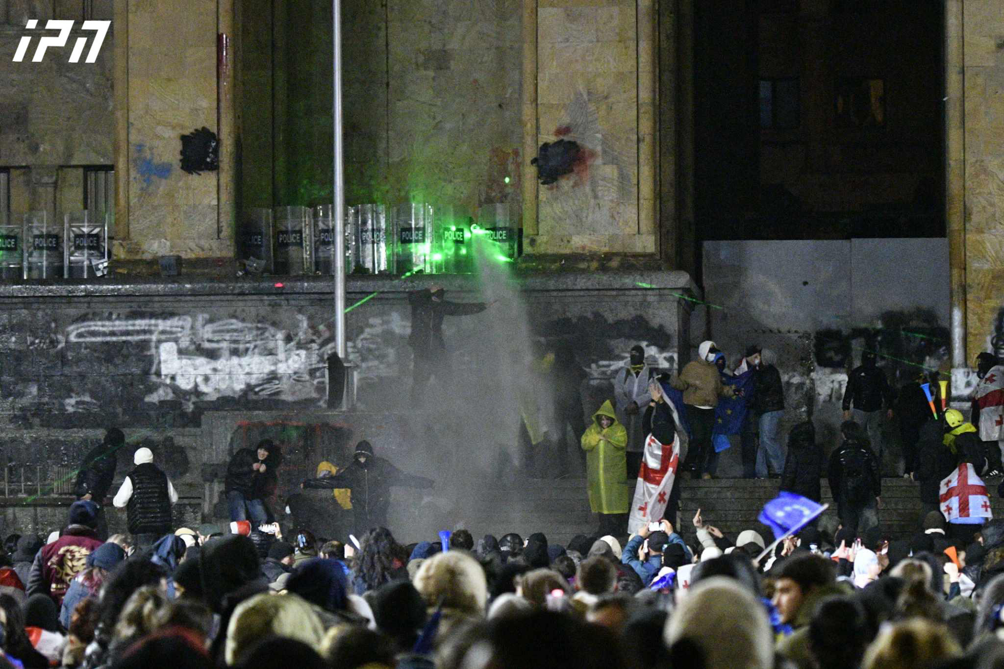 მომიტინგეები წყლის ჭავლის გაშვების შემდეგ წყალს სათლებში იღებენ და სპეცრაზმელებს უკან ასხამენ